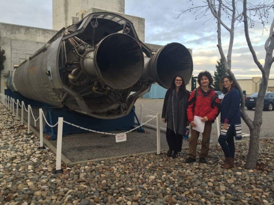 An old Titan 1 rocket with two students and a mentor standing in front of it.